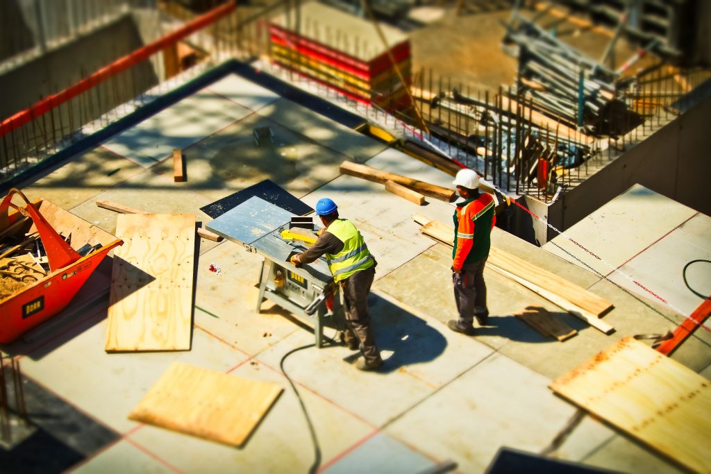 Two construction workers in high-visibility gear on a building site