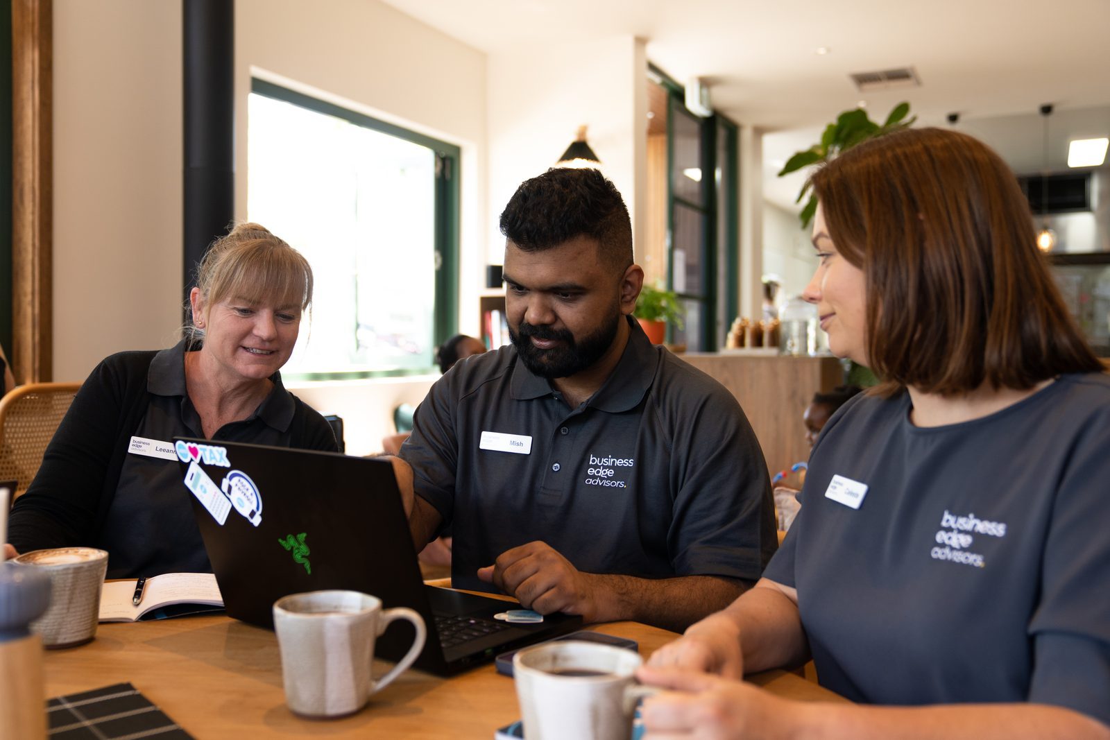 Three Business Edge Advisors staff working together at a table with laptops