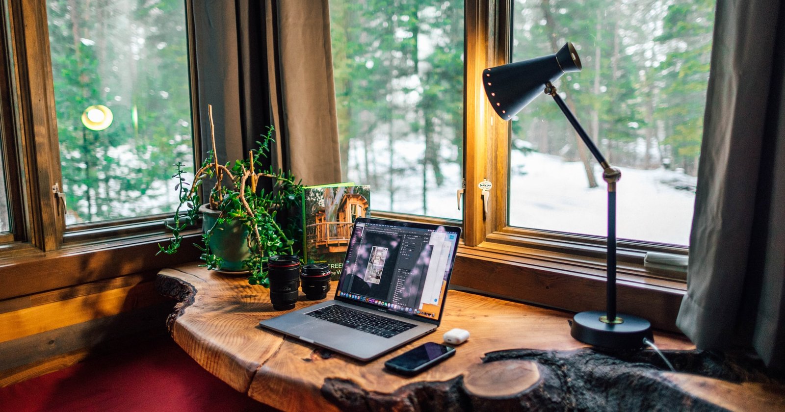 A laptop and smartphone on a rustic wooden desk in a home workspace